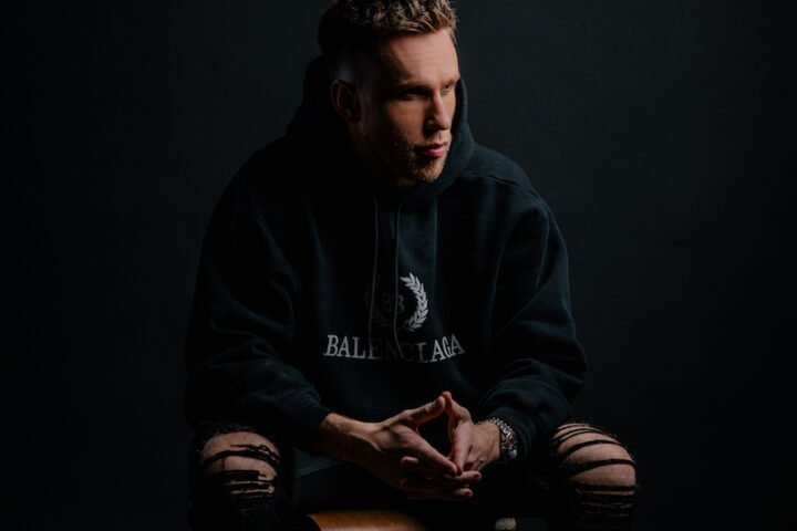 Nicky Romero press photo sitting in a chair.