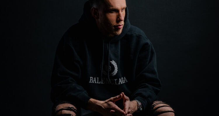 Nicky Romero press photo sitting in a chair.