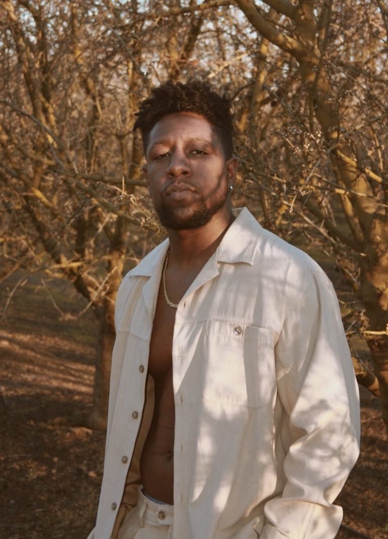 Aussie Aus's press photo outside with his shirt open.