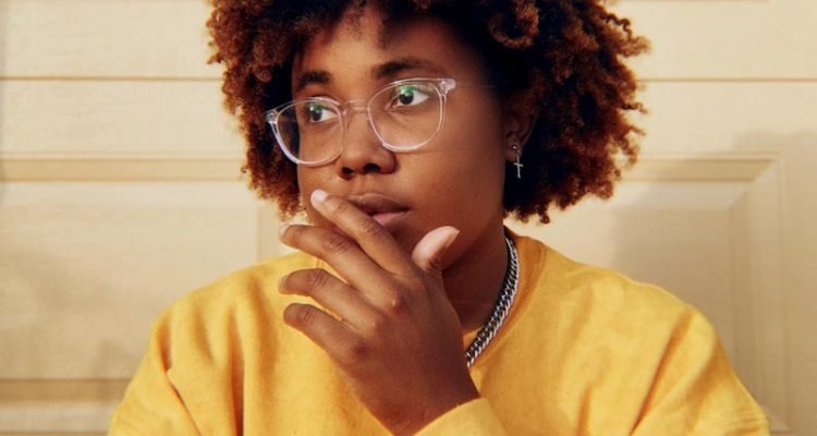 Justy press photo wearing a yellow sweater.