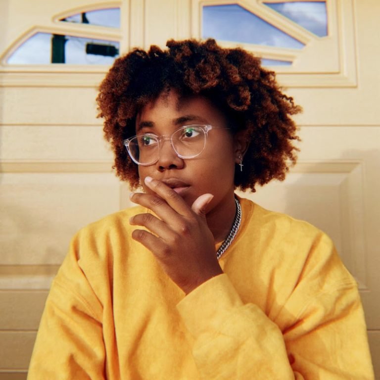 Justy press photo wearing a yellow sweater.
