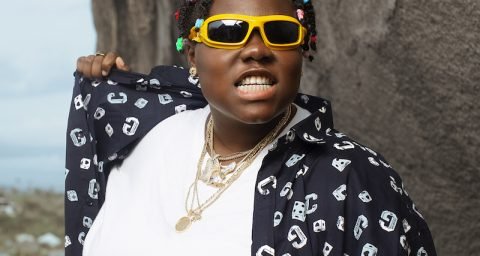 Teni The Entertainer press photo outside with yellow sunglasses on.
