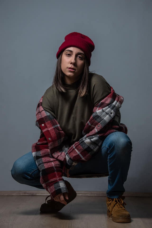 Andrea press photo in the studio wearing a red beanie 