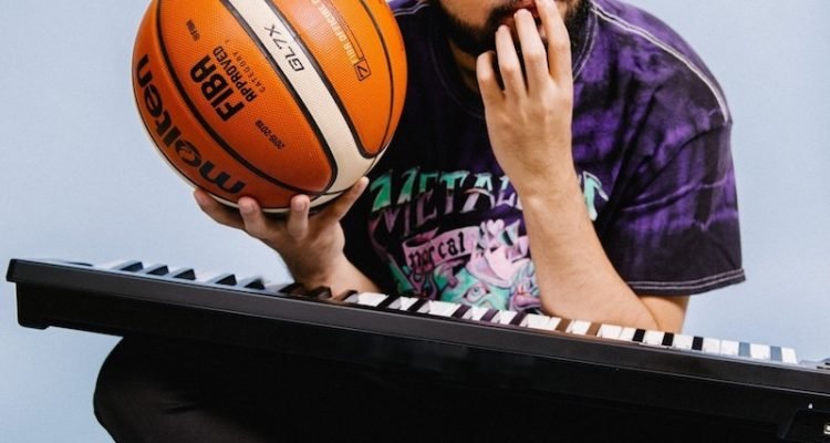 KyleYouMadeThat press photo holding a basketball and a keyboard resting on his lap