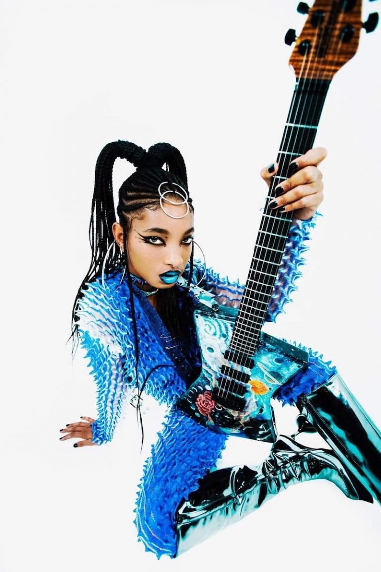 WILLOW press photo wearing a colorful futuristic outfit holding an electric guitar