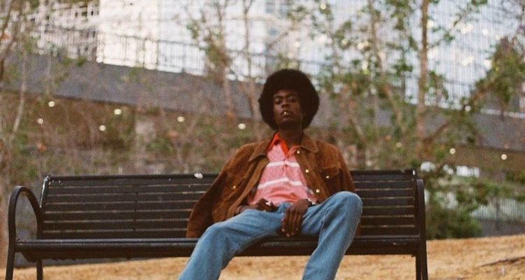 PawPaw Rod press photo outside wearing a brown jacket with matching cowboy boots
