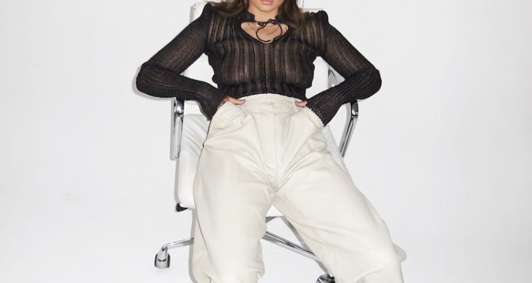 RoseeLu press photo sitting in a chair wearing a black and beige outfit wearing