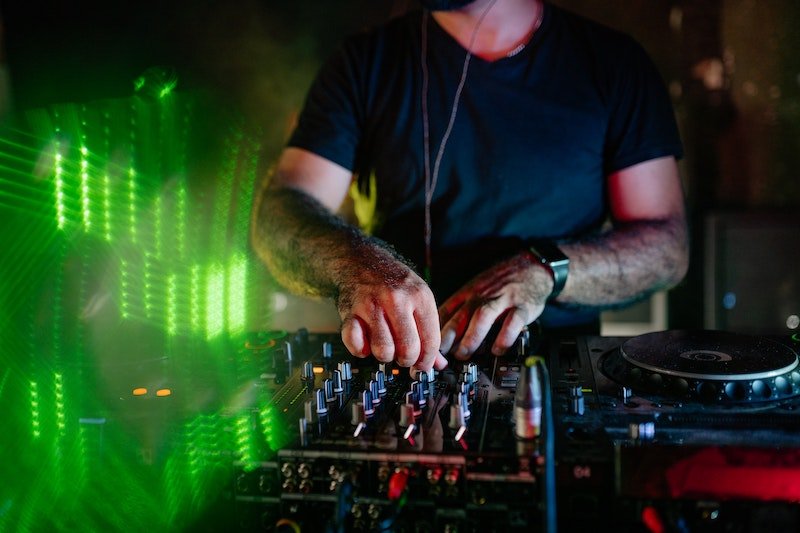man in black crew neck t-shirt wearing black sunglasses playing DJ mixer
