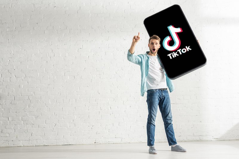 Happy man holding big model smartphone with TikTok app — Photo by HayDmitriy