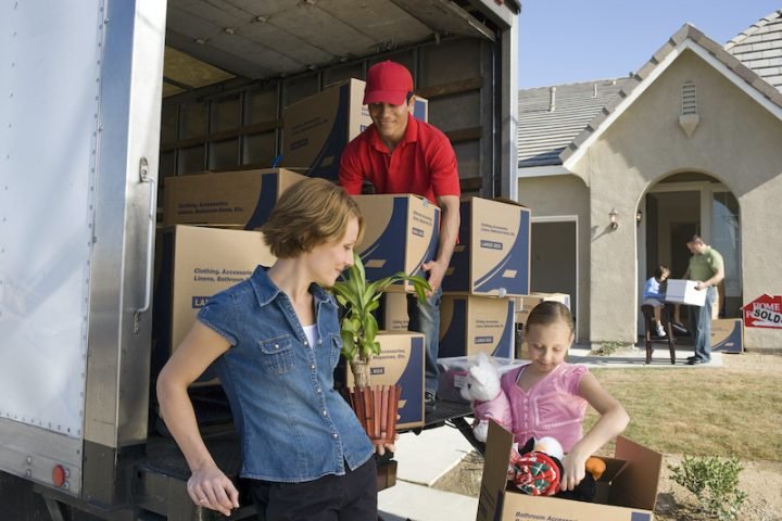 Family and worker unloading truck of cardboard boxes