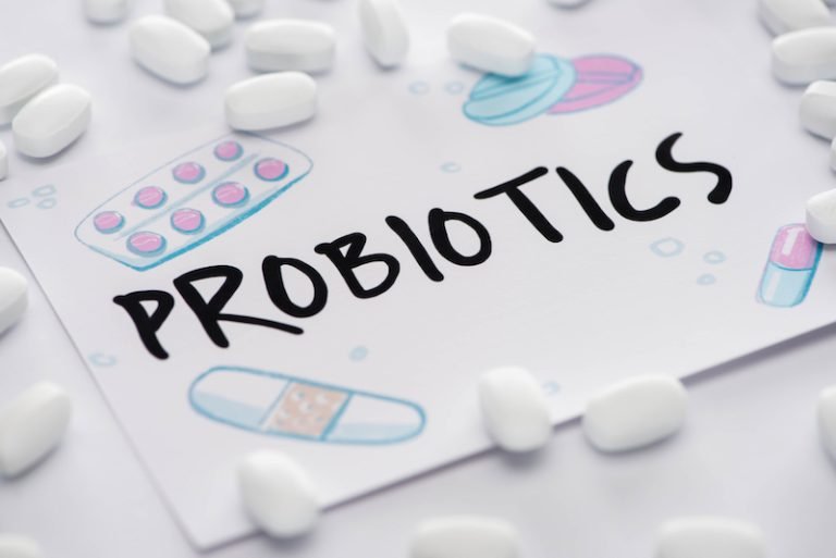 Selective focus of drawing with probiotics lettering near pills on white background