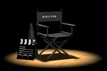 Director's chair with megaphone and clapper board on a wood floor under a spotlight