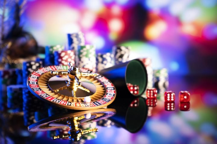 Gambling theme. Dice, roulette wheel and poker chips on color bokeh background.