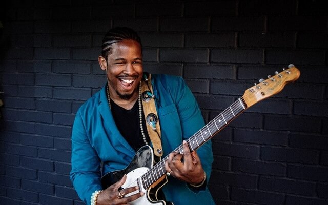 Quentin Moore press photo holding a guitar